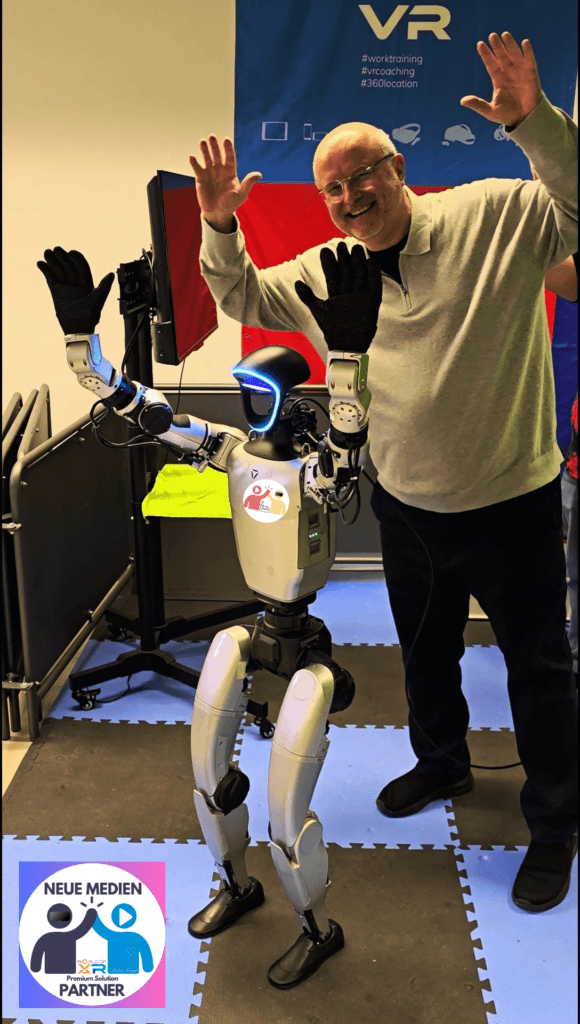 Eugene und Markus grüßen - Neue Medien Partner A friendly humanoid robot with illuminated blue visor stands beside a smiling man raising his hands in a tech showcase booth.